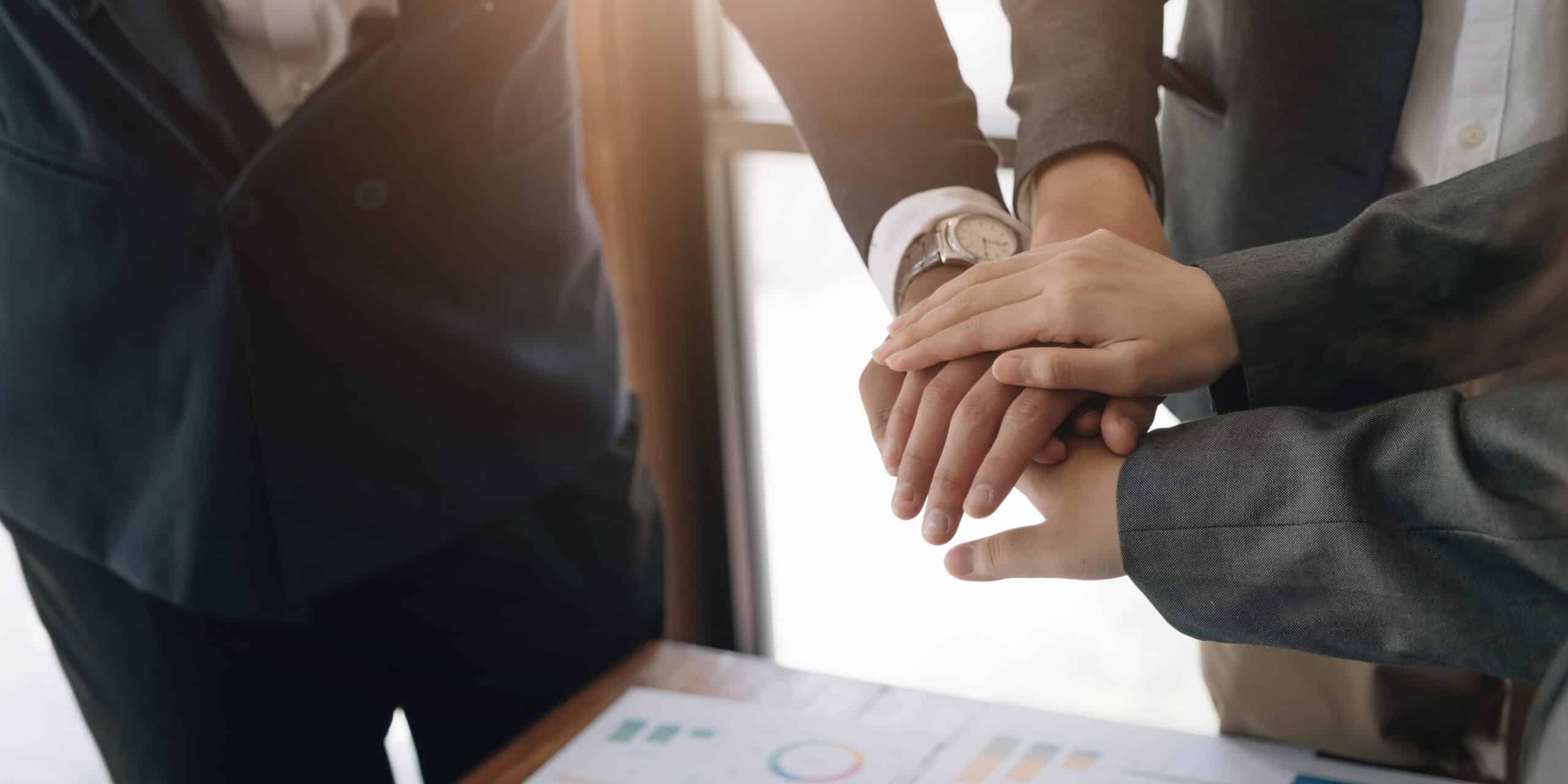 Close up of young business people putting hands together showing integrity.